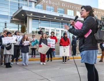 Jessie Shapiro speaks into a microphone in front of protesters at the School District of Philadelphia