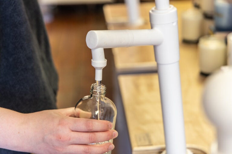 Emma Gardner refills a glass bottle with lavender laundry detergent at Ray’s Reusables store in Philadelphia’s Northern Liberties neighborhood. (Kimberly Paynter/WHYY)