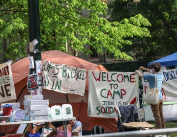 Members of a protest encampment at UPenn hang signs around their camp on May 1, 2024.