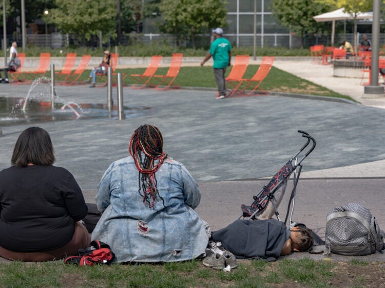 2 woman with a young child sitting on the ground in the park.