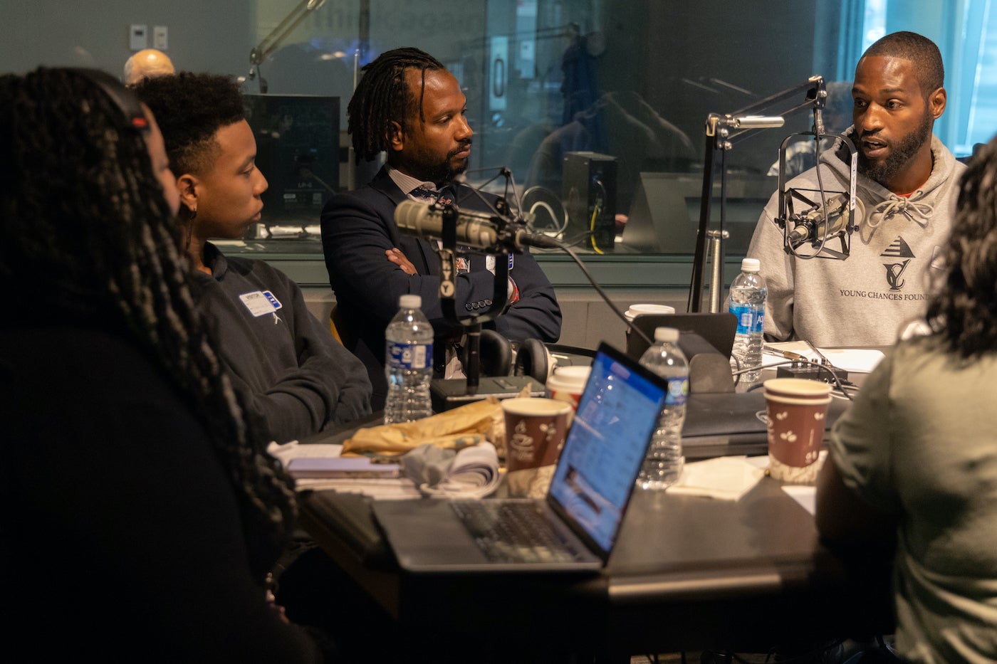 A group of people speak into microphones at a roundtable discussion.