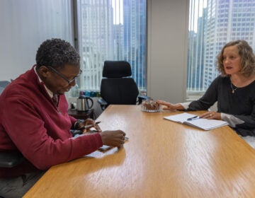 Elizabeth Hersh (right) is seated across the table from David Holloman (left) as they look over notes