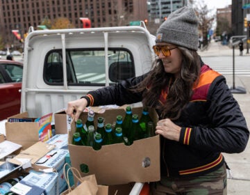 Melissa Lynn Torre, founder of the Vellum Street Soap Company, with recycled glass jars and bottles she uses to package the skin products she creates and sells. (Kimberly Paynter/WHYY)