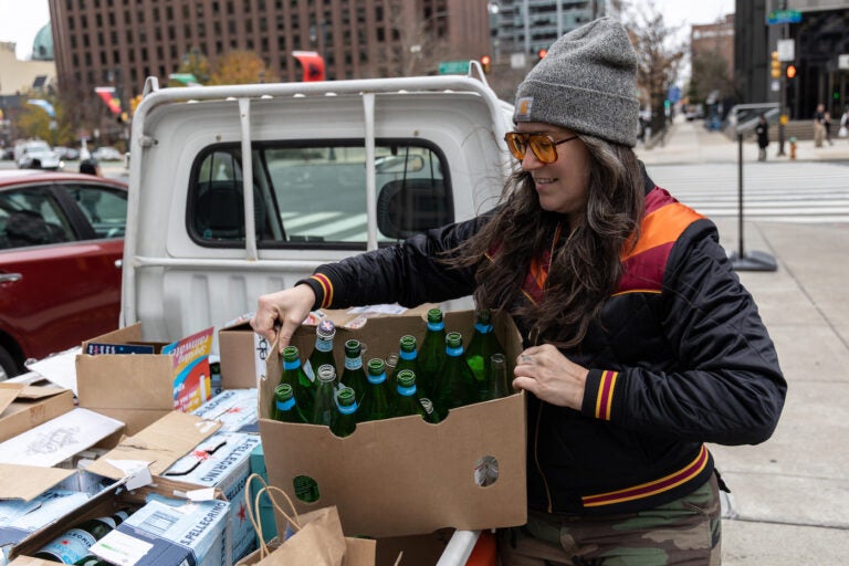 Melissa Lynn Torre, founder of the Vellum Street Soap Company, with recycled glass jars and bottles she uses to package the skin products she creates and sells. (Kimberly Paynter/WHYY)