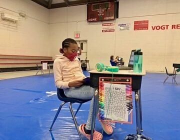 Faith Allen, 10, reads at her desk in Vogt access center gymnasium. (Emily Rizzo/WHYY)