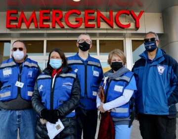 Volunteers from the Delaware County Medical Reserve Corps stand outside the Crozer Emergency Room, where they are needed to help the hospital cope with a flood of COVID-19 patients. They are (from left) Ken Barton, Marlynn Orlando, Georg Strey, Nancy Niemiec, and Dennis Daye.(Emma Lee/WHYY)