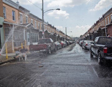 man sits on a chair in the path of a fire hydrant's spray