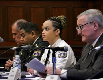 A row of people sit at a table with microphones in front of them.