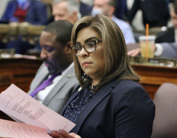 Councilmember Lozada reviews papers while seated at her desk in council chambers.