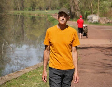 Neil King walking on a path along a river.