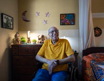 Alex Morisey sits in his wheelchair in his room, smiling.