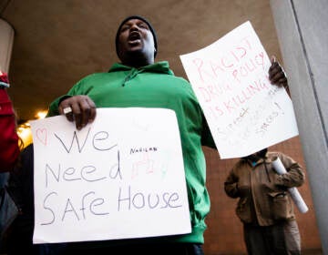 A protester holds signs in support of a supervised injection site