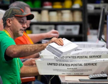 A man scans a mail ballot.