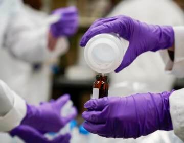 Eva Stebel, water researcher, pours a water sample into a smaller glass container for experimentation as part of drinking water and PFAS research at the U.S. Environmental Protection Agency Center For Environmental Solutions and Emergency Response