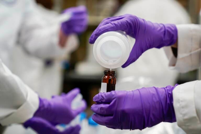 Eva Stebel, water researcher, pours a water sample into a smaller glass container for experimentation as part of drinking water and PFAS research at the U.S. Environmental Protection Agency Center For Environmental Solutions and Emergency Response