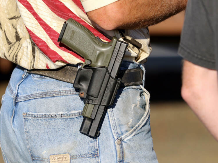 In this Oct. 9, 2015 file photo, Michael Johnson wears a firearm as he waits outside of Roseburg Municipal Airport in Roseburg, Ore.