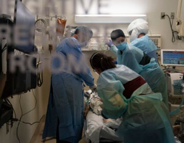 Health care workers treat a patient who tested positive for the coronavirus last week at Providence Holy Cross Medical Center in Los Angeles. California has imposed an overnight curfew on most residents as the most populous state tries to head off a surge in the coronavirus.