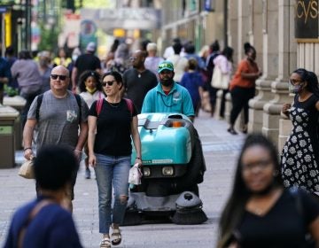 People, some without masks, walk along Market Street