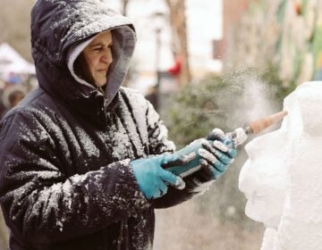 A person carves an ice sculpture