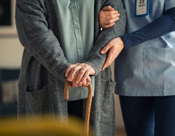 Close up hands of caregiver doctor helping old woman at clinic.