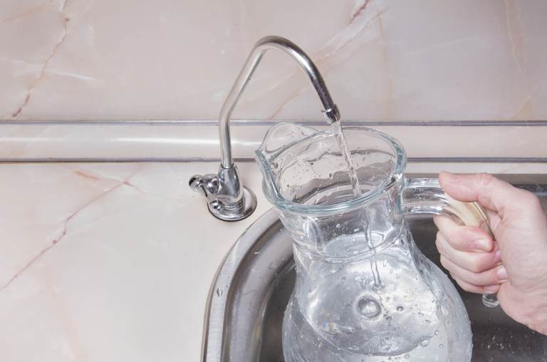 A person fills up a jug of water from a faucet.