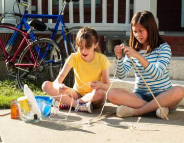 Two girls using rope to create an educational project outside