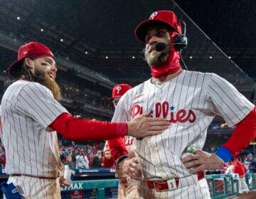 Philadelphia Phillies' Bryce Harper, right, gets interviewed as Brandon Marsh, left, and Bryson Stott, center, celebrate with him following the baseball game against the Cincinnati Reds, Tuesday, April 2, 2024, in Philadelphia.