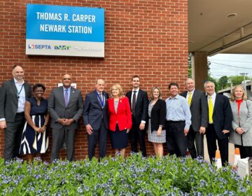 Tom Carper posing with people in front of the station