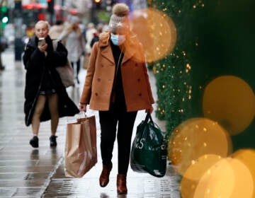 A woman wearing a face mask carries shopping bags along Oxford Street