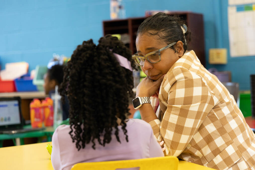 Nicole Miller sitting with a student at a small table