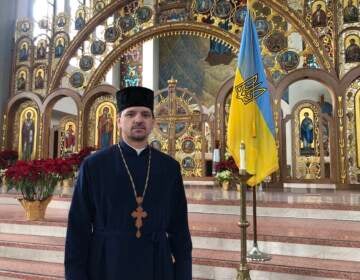 Father Roman Pitula of the Philadelphia Ukrainian Catholic Church, standing near a candle the church lit to pray for Ukraine