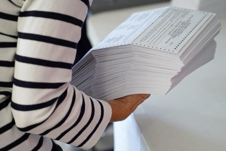 A woman is holding a stack of mail ballots