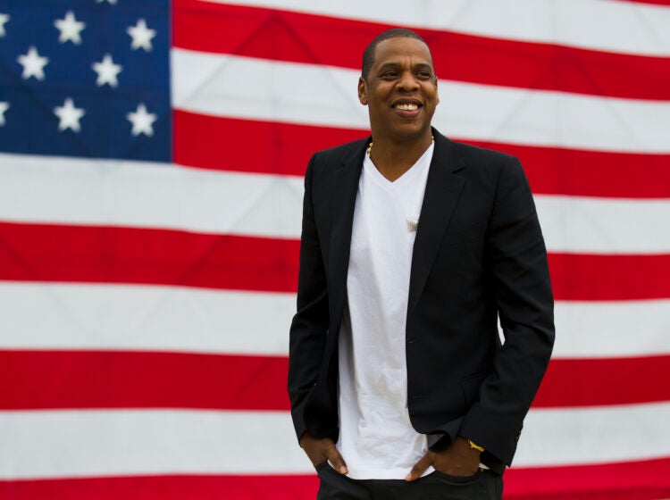 Jay-Z standing in front of a large American flag