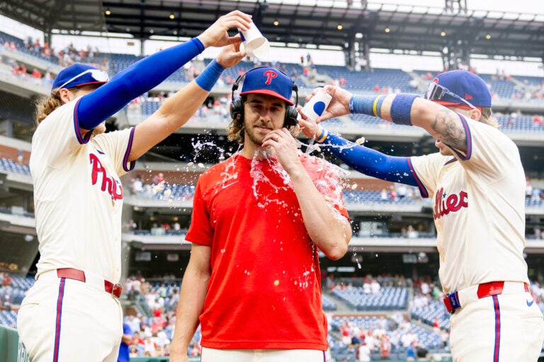 Philadelphia Phillies starting pitcher Aaron Nola is doused with water by Alec Bohm, left, and Bryson Stot