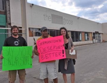 From left, Geir Overland, Pedro Rodriguez, and Donna Uettwiller hold signs on the sidewalk in front of Chelten Plaza. (Kristen Mosbrucker/for NewsWorks)