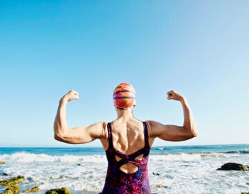 A woman flexes her arms before entering the ocean