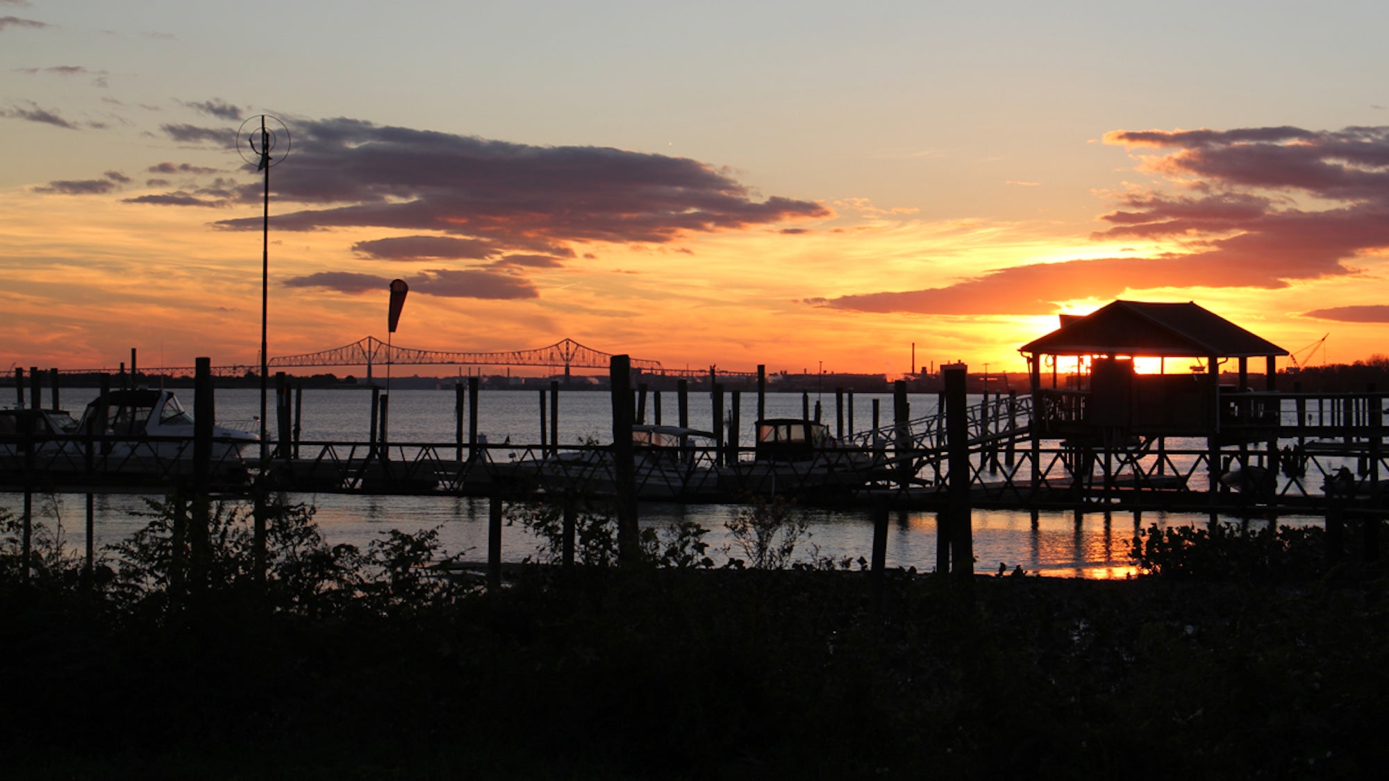 The sun sets behind the docks at the Riverside Yacht Club on the Delaware River in Tinicum. (Emma Lee/WHYY)