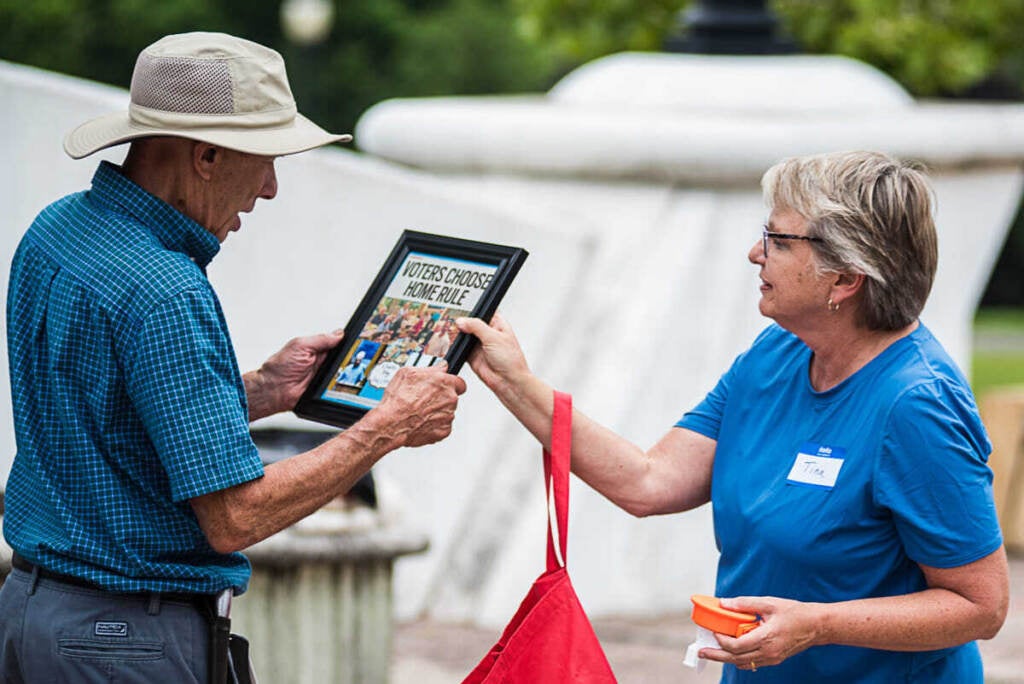 Tow residents look at a sign that reads Home Rule Charter.