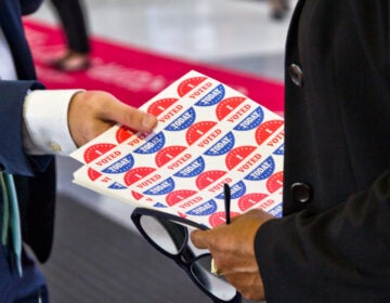 An election worker hands a sheet of 