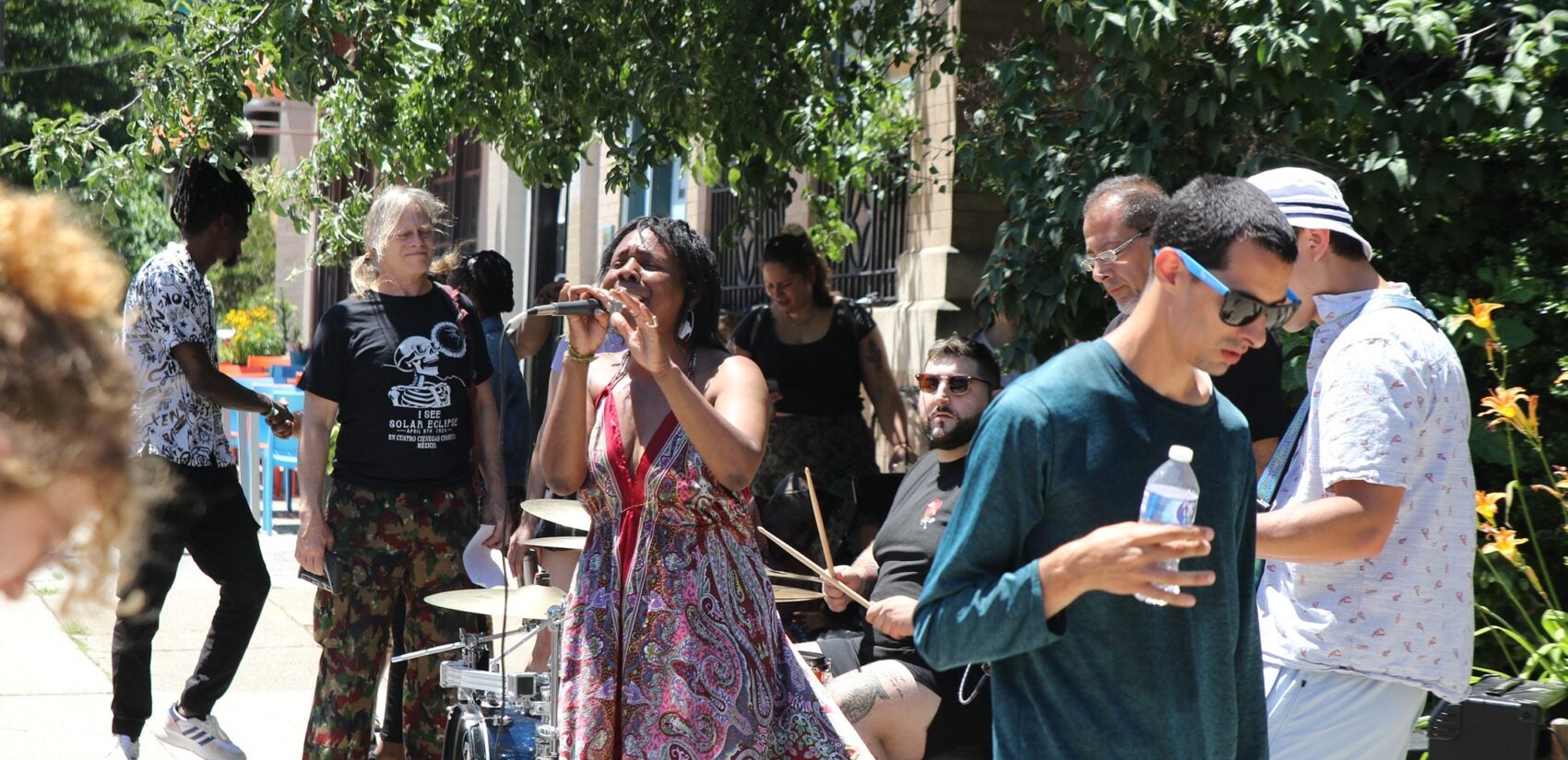 a woman sings as people walk by