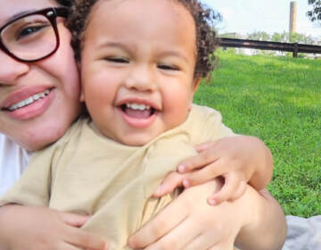 A teenager girl holding and tickling with her younger sibling outside