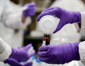 A water researcher pours a water sample into a smaller glass container for experimentation as part of drinking water and PFAS research