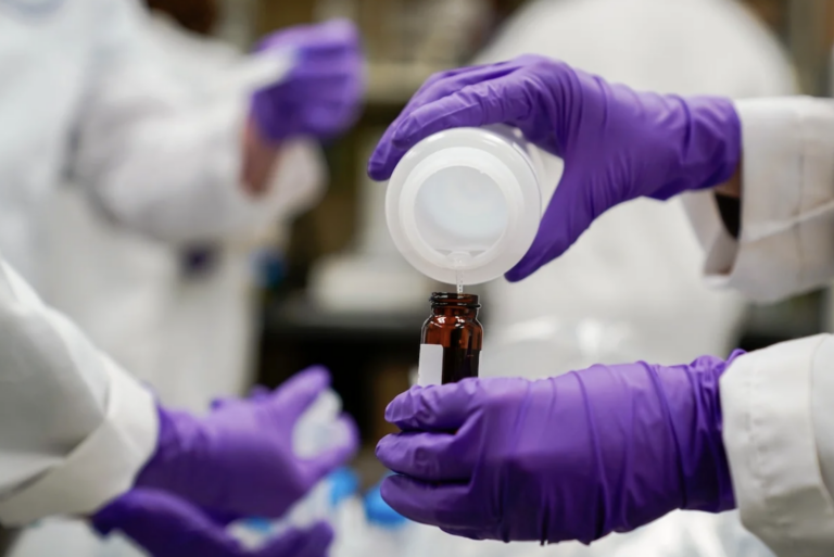 A water researcher pours a water sample into a smaller glass container for experimentation as part of drinking water and PFAS research