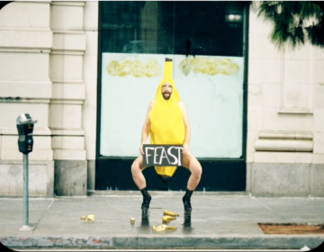 A person in a banana costume holding a sign that says 